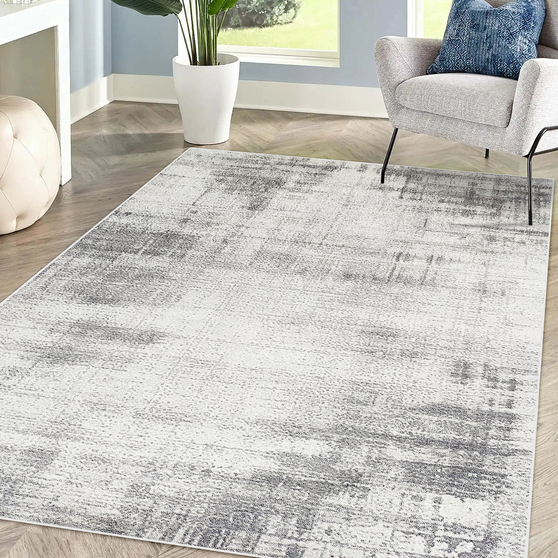 Franco 200x300cm Large Tufted Contemporary Indoor Rug with abstract pattern on herringbone floor, next to a modern armchair and cream ottoman, enhancing the cozy sitting area.