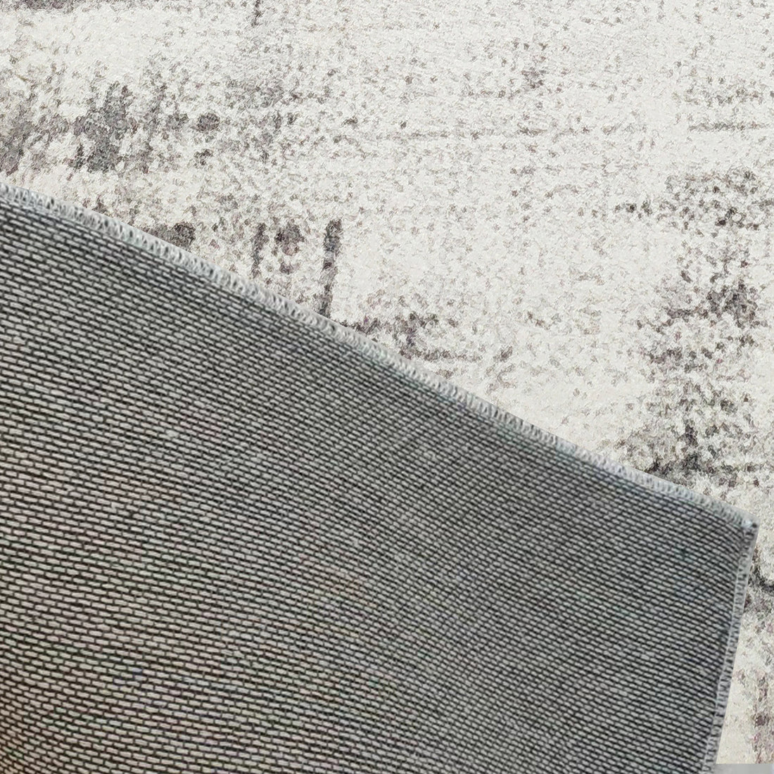 Franco 200x300cm Large Tufted Contemporary Indoor Rug, showcasing its backside, sits atop a larger mottled grey/cream carpet, highlighting its tightly woven texture and substantial size.