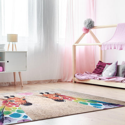 Giraffe 160x230cm Medium Kids Printed Indoor Rug on light wood floor, featuring two watercolor-style rainbow-spotted giraffes nuzzling, in a softly lit playroom with a house-shaped bed and storage cabinet.