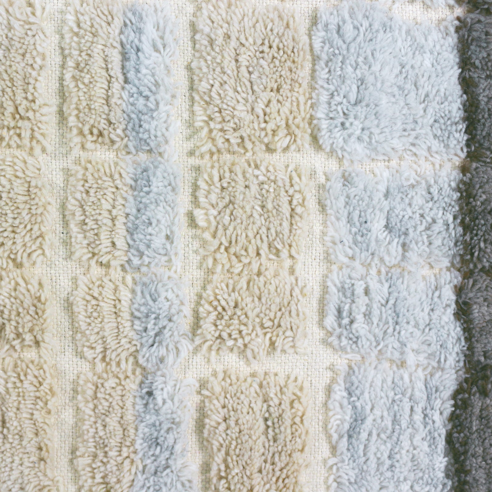 Close-up of the Isaac 120x180cm Abstract Wool Blend Handwoven Shag Rug, showcasing its textured tufted squares in a grid pattern, reflecting the intricate handwoven craftsmanship and soft plush design.