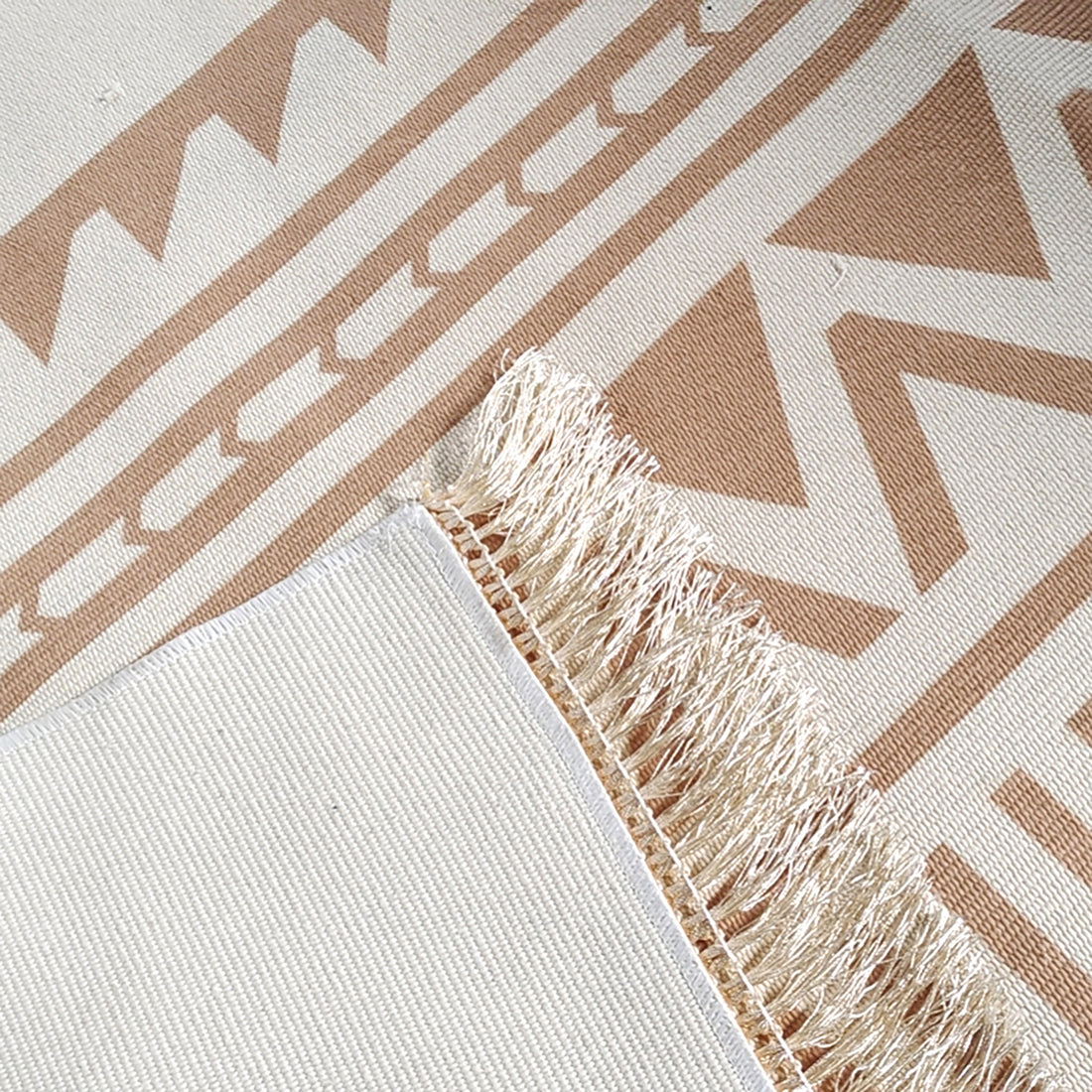 Close-up of Kaley 200x300cm Woven Cotton Blend Tasseled Indoor Rug featuring a beige-and-white geometric pattern with zig-zags and triangles, tasseled edges, and a tightly woven backing.