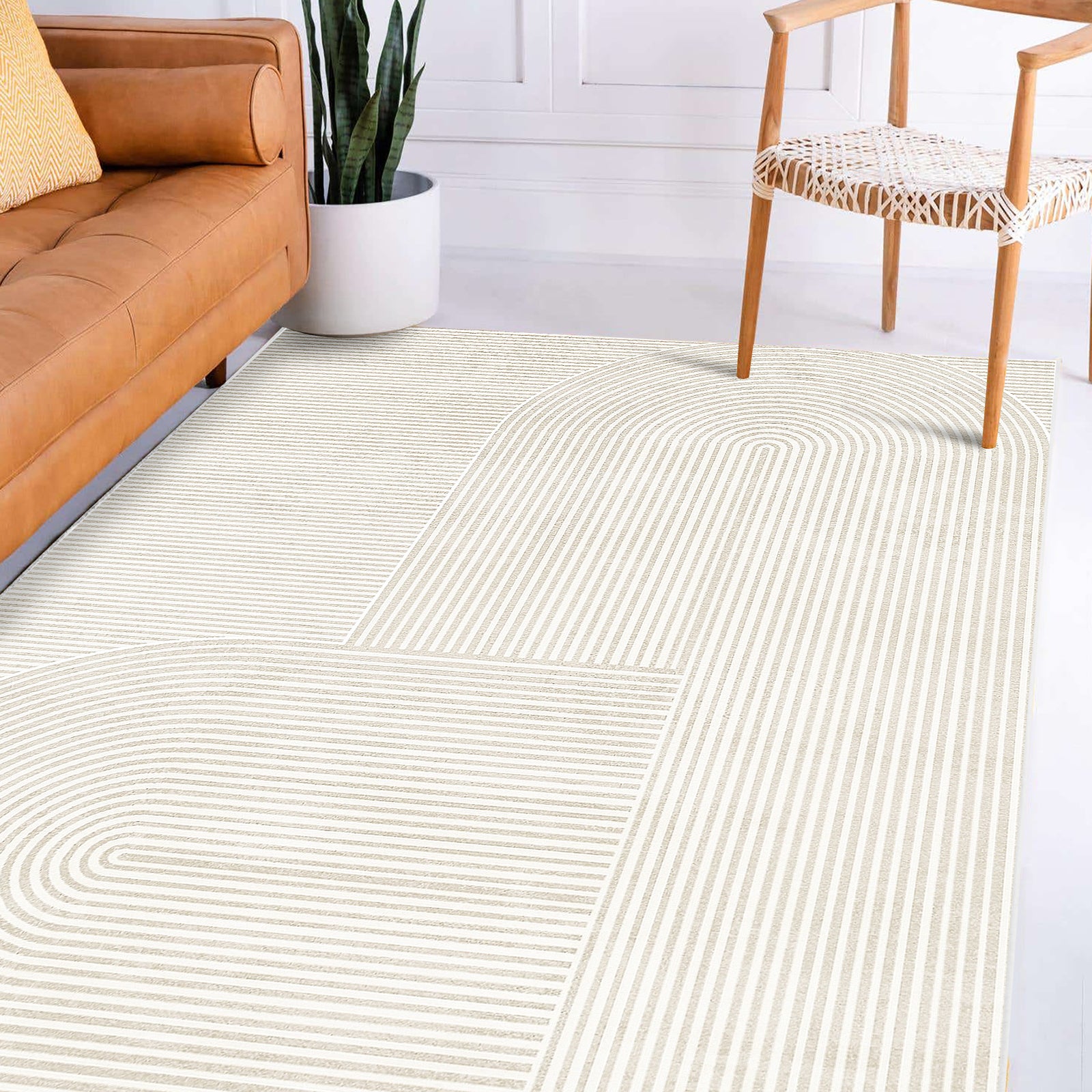 Krokom 120x180cm Modern Abstract Indoor Floor Rug with cream-and-beige arched-stripe pattern in a minimalist living area, complemented by a tan leather sofa and snake plant.