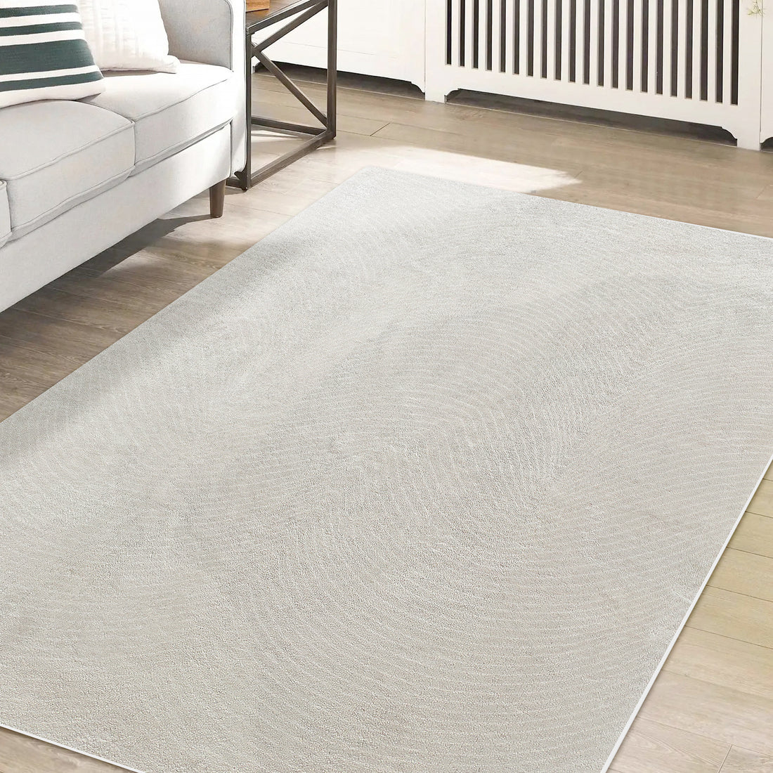 Lita Modern Abstract Tufted Rug 120x180cm in light-beige with subtle swirl texture, on hardwood floor, complements a minimalist living room setup with a gray sofa and sleek side table.