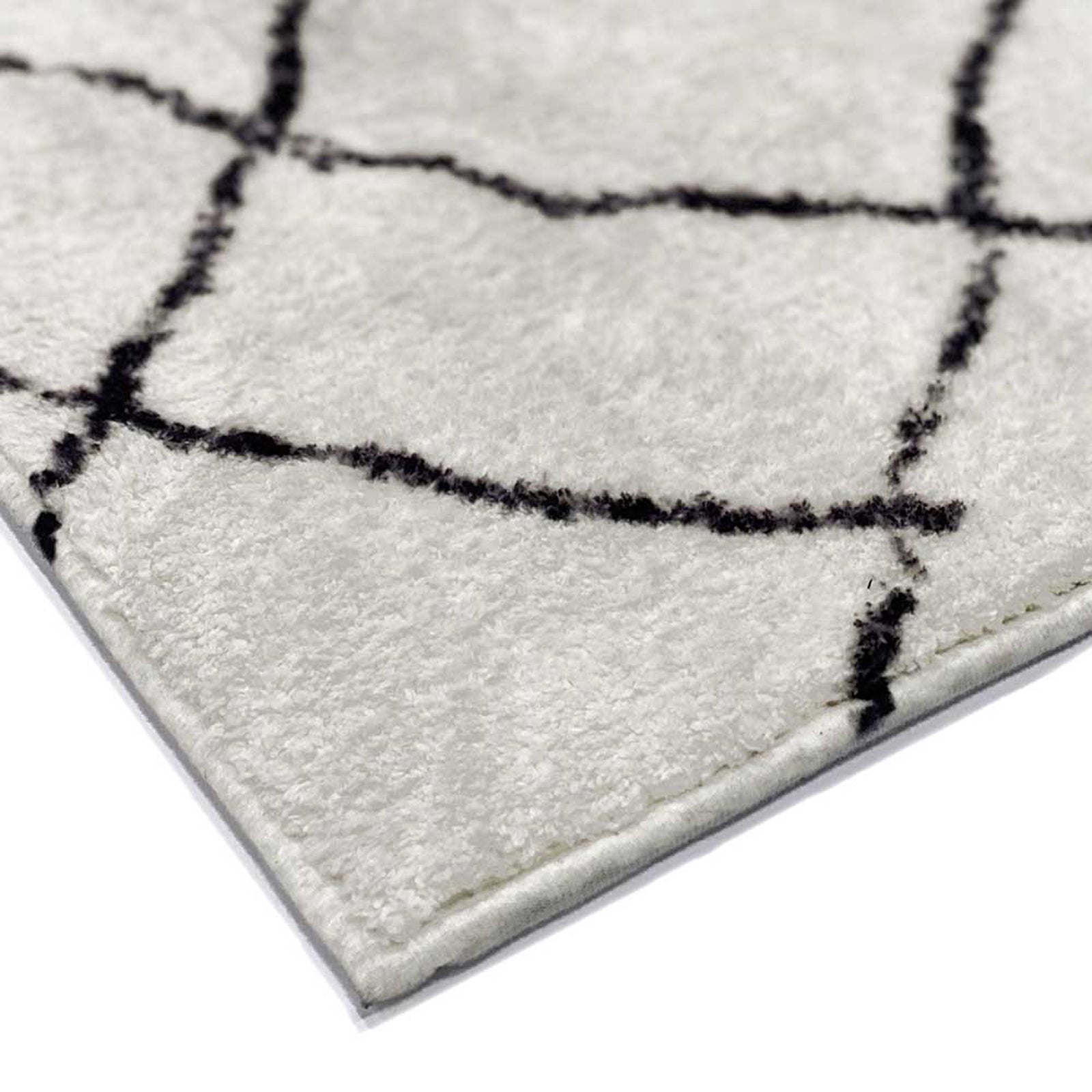 Melody Black and White Modern Floor Rug 200 x 300cm, showcasing a close-up of its cream surface with a black grid pattern, revealing pile texture and edge stitching.