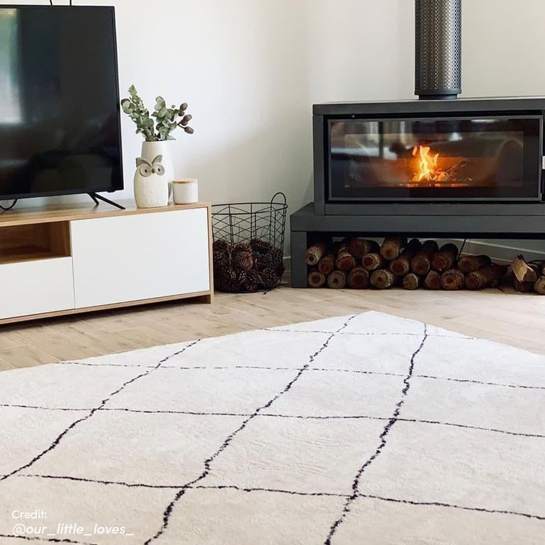 Milani 120x170cm Contemporary Printed Indoor Floor Rug with a black grid pattern on a light-cream background, enhancing a cozy living room corner with Scandinavian-inspired design.