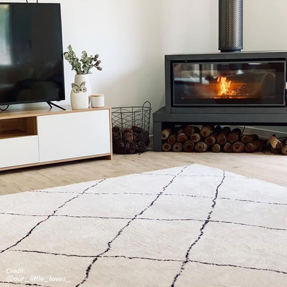 Milani 120x170cm Contemporary Printed Indoor Floor Rug with a black grid pattern on a light-cream background, enhancing a cozy living room corner with Scandinavian-inspired design.