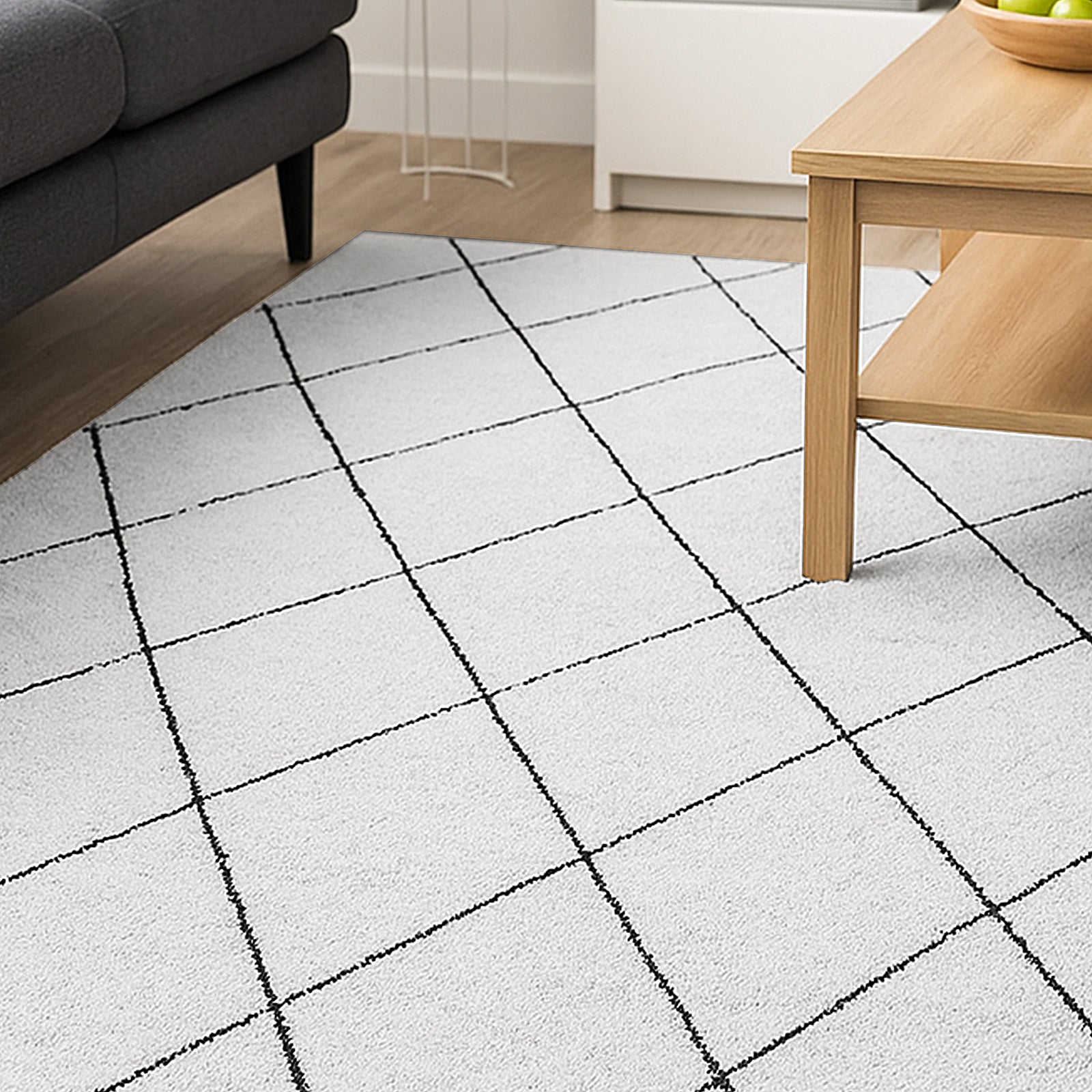 Milani 200x300cm Contemporary Printed Indoor Floor Rug with a black grid pattern on a white background, partially under a light wood coffee table, harmonizing a modern Scandinavian-style with the dark gray sofa.