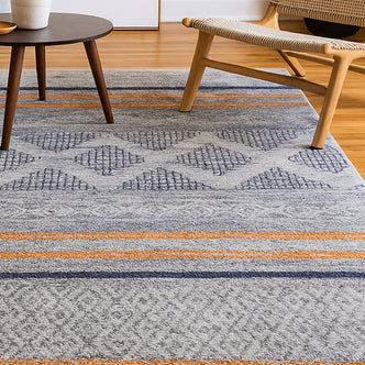 Close-up of the Naomi Scandinavian Style Modern Rug 120x170cm, featuring a tribal-inspired print and textured surface, partially placed under a chair on a rug, highlighting its stylish design and quality weave.