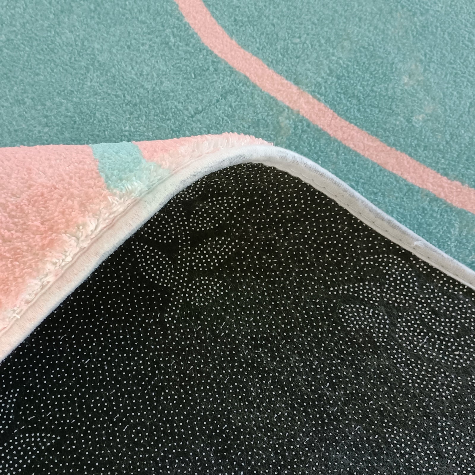 Narsen 120x170cm Kids Modern Abstract Floor Rug with pink and mint green tones, non-slip black dot-patterned backing, displayed on teal carpet with pink lines, corner flipped to show backing.