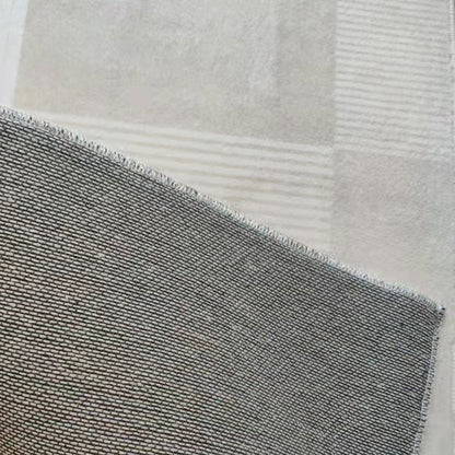 Close-up of the Nicho 200x300cm Polyester Tufted Modern Abstract Indoor Rug, showcasing its dark-gray woven pattern with overlocked edges atop a lighter fabric, highlighting the rug's modern abstract design.