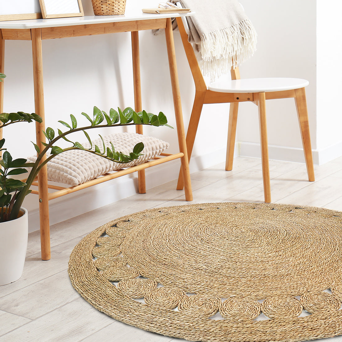 Ophelia 180cm Round Textured Seagrass Indoor Rug in Natural, featuring a braided design with a simple scalloped border, lies in a Scandinavian-inspired, minimalist room setting.