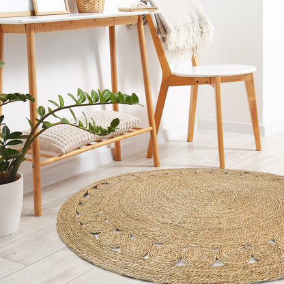 Ophelia 180cm Round Textured Seagrass Indoor Rug in Natural, featuring a braided design with a simple scalloped border, lies in a Scandinavian-inspired, minimalist room setting.