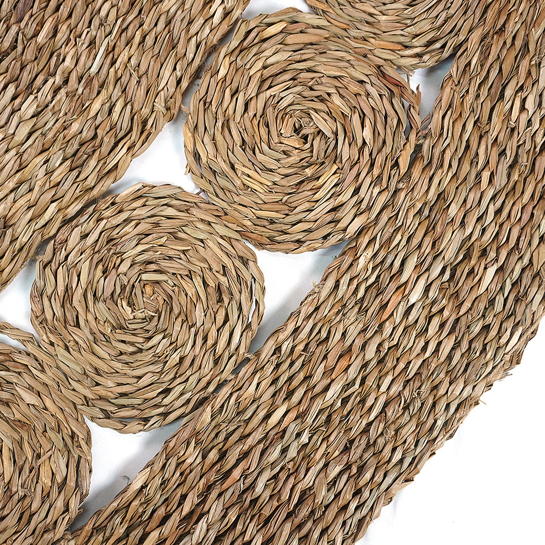 Close-up of the Ophelia 180cm Round Textured Seagrass Indoor Rug in Natural, showcasing its intricate braided spiral and rope-like textures, capturing the detailed craftsmanship of this handmade piece.