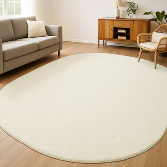 Pavla 200 x 300cm Oval Soft Rug in Beige, a plush, cream-colored centerpiece, lies elegantly over hardwood flooring, enhancing a minimalist living room with its cozy, inviting texture and unique oval shape.