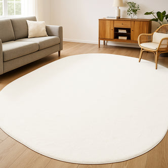 Pavla 240 x 330cm Oval Shaggy Rug in Cream White softens a light-wood floor, adding plush texture and minimalist elegance to a bright living room with modern furniture and gentle daylight.