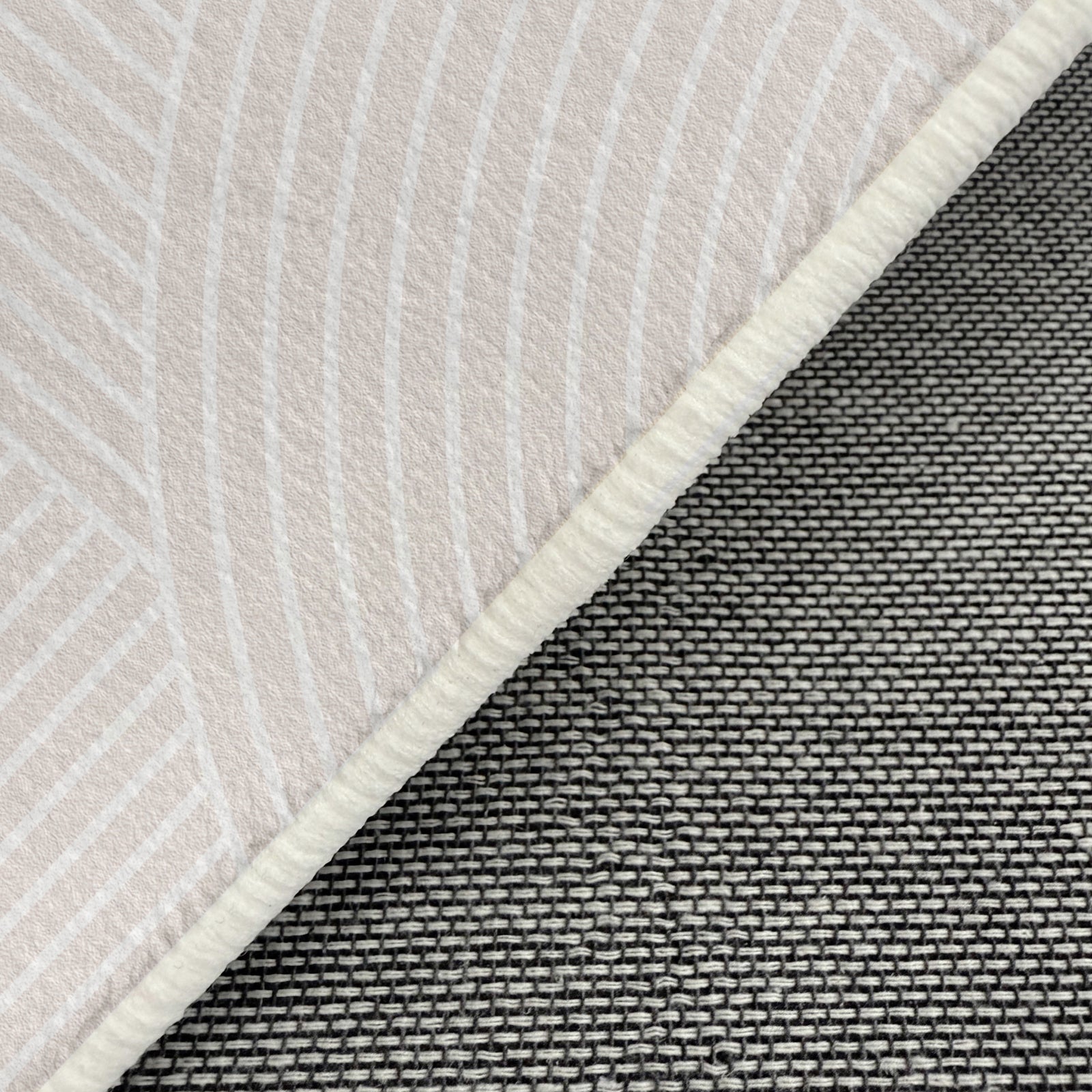 Close-up of the Penina 240 x 330cm Cloud Shaggy Rug in Neutral, showing its light fabric with curved stripes, woven non-slip backing, and stitched edge binding for a cosy, stylish touch.