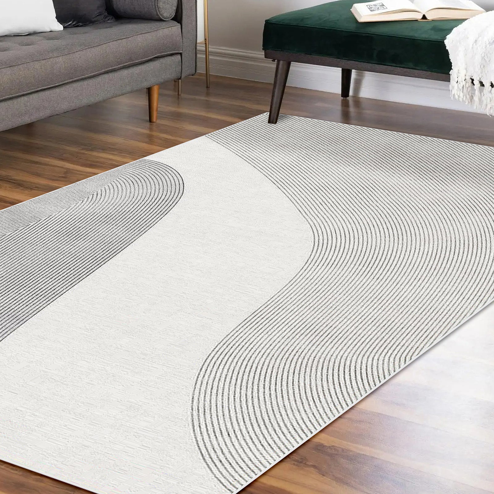 Ramvik 160x230cm Abstract Indoor Floor Rug on hardwood floor, featuring subtly textured gray lines. Nearby are a gray sofa with pillows and a dark green velvet bench with a draped white throw.