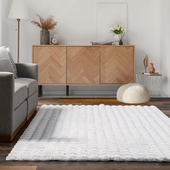 Severa 180x300cm Fluffy Textured Bubble Rug in White, featuring a plush, scalloped texture, placed over dark wood flooring in a bright, minimally-styled living room corner.