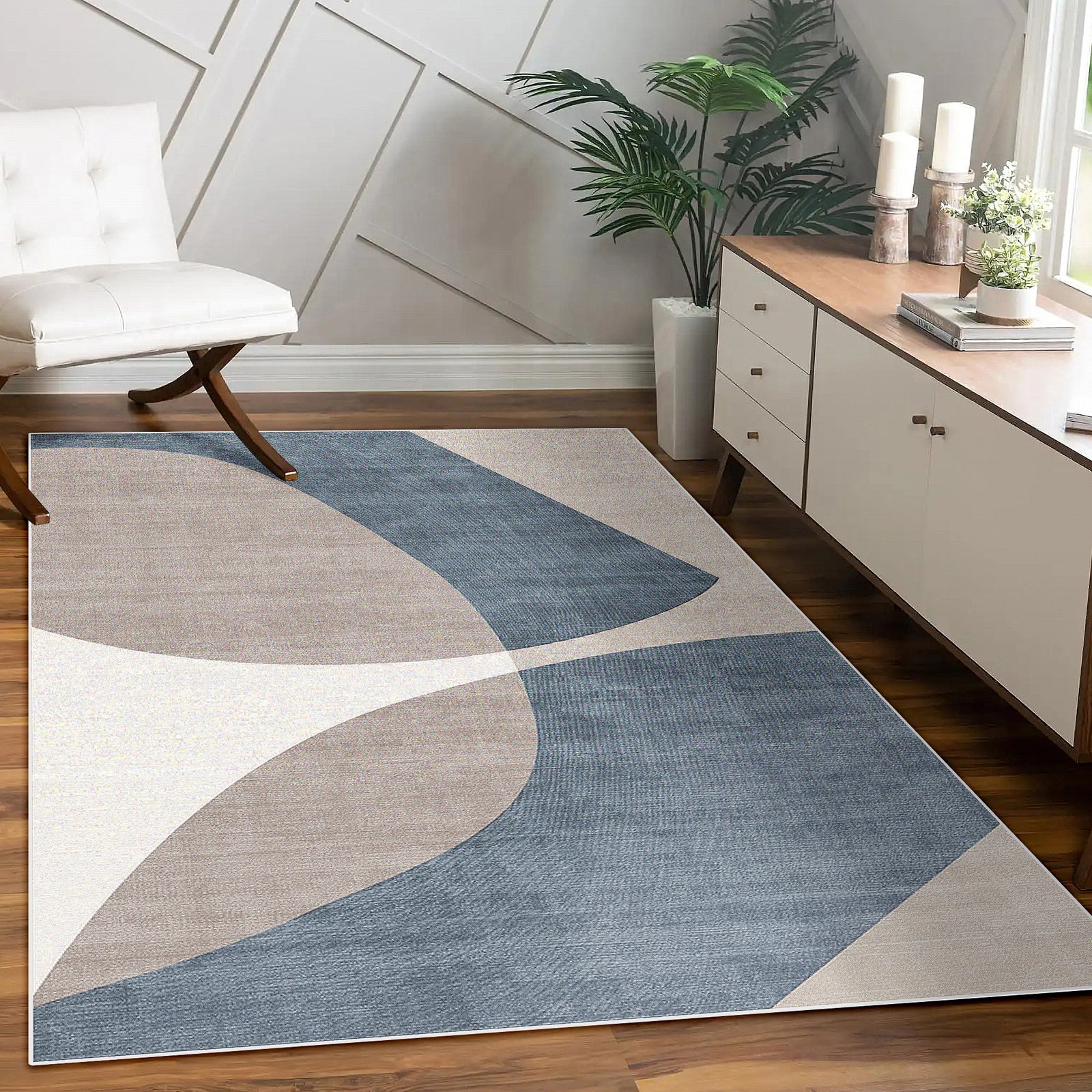 Sharya 160x230cm Abstract Indoor Floor Rug with overlapping-arc pattern in blue, beige, and off-white, placed in a modern room, complemented by a console, lounge chair, and potted plants.