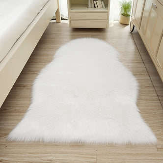 Silvanus 60x90cm Shaggy Soft Fluffy Fur Rug in White, placed centrally on a light wood floor, enhancing the cosy, softly-lit bedroom ambiance with its plush, sheepskin-style texture.