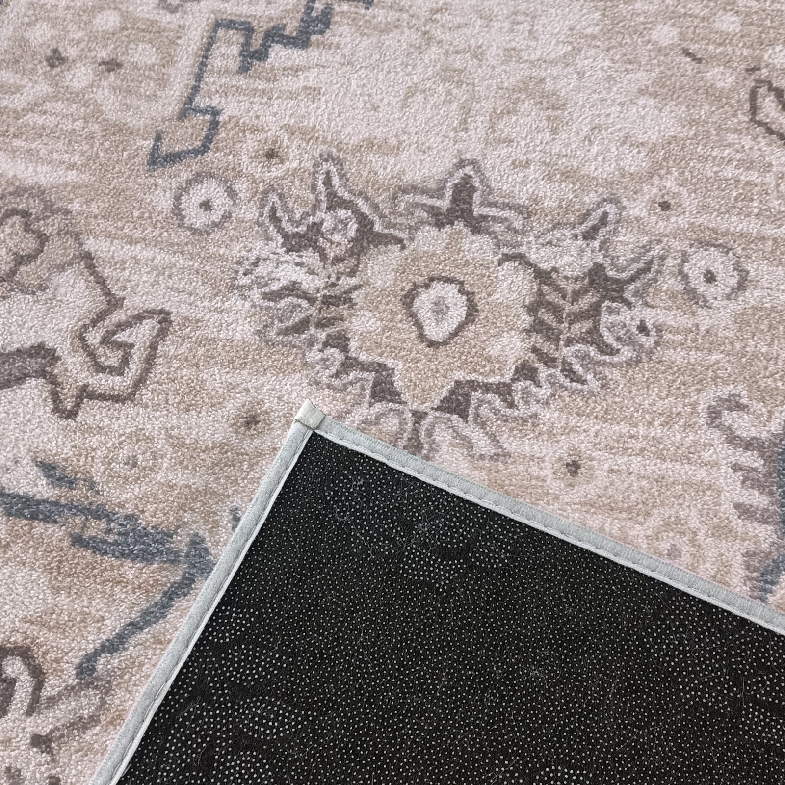 Trolvik 160x230cm Medium Persian Indoor Floor Rug with a beige/gray floral-geometric pattern, showcasing a corner flipped to reveal its black, dot-patterned non-slip backing, highlighting craftsmanship and modern elegance.