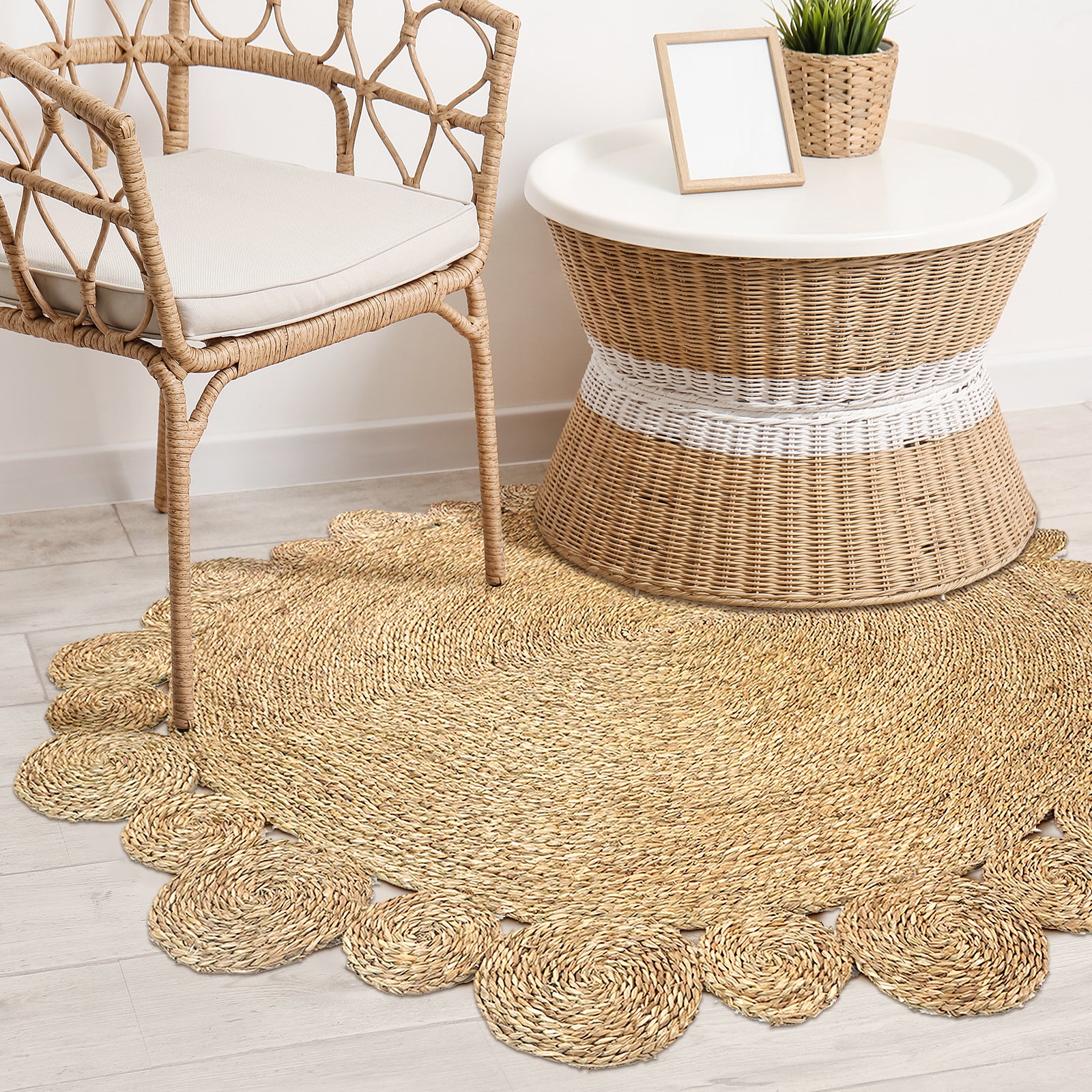 Una 180cm Seagrass Rug - Brown displayed under a boho-inspired setting with a woven rattan armchair, drum-shaped side table, and a cozy, braided design featuring scalloped edges.