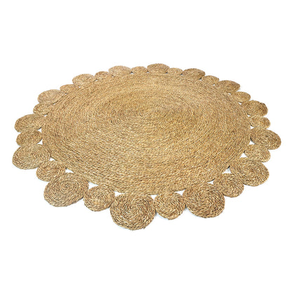Una 180cm Seagrass Rug - Brown, featuring a round, braided design with concentric spiral patterns and a scalloped border of smaller circular coils, showcasing its intricate handmade craftsmanship.