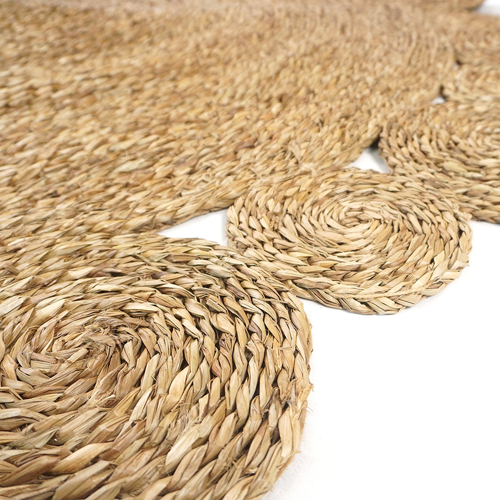 Close-up of the Una 180cm Seagrass Rug - Brown, showcasing its intricately braided natural-fiber spirals, forming a cohesive, handmade design ideal for enhancing any living space's decor.