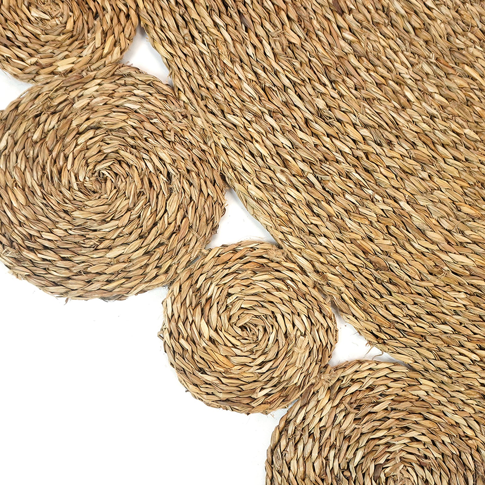 Una 180cm Round Textured Seagrass Indoor Rug in Natural, featuring a handmade spiral-braided design with overlapping circular pieces, displayed against a white background, highlighting its intricate and unique craftsmanship.