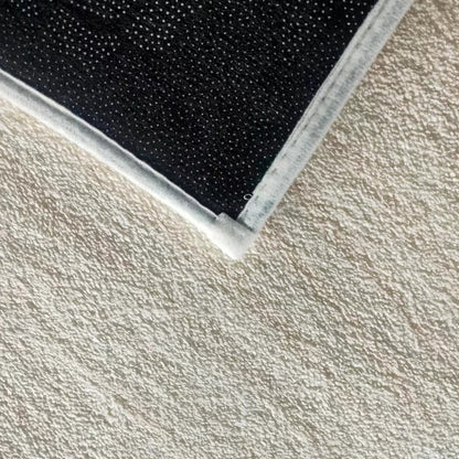Vastra Modern Abstract Floor Rug 160 x 230cm features a black, rubber-dotted non-slip backing with white fabric edging, shown close-up on a beige textured carpet, highlighting its secure and modern design.
