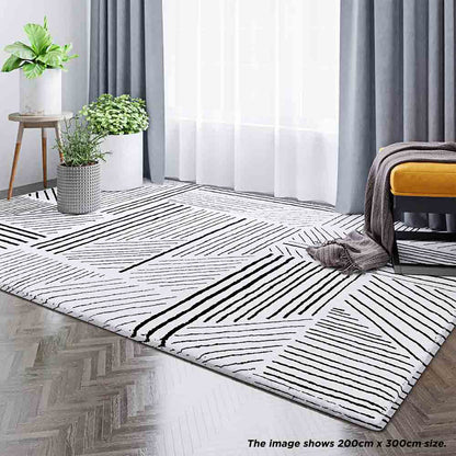 Vikki 200x300cm Abstract Contemporary Floor Rug with black-and-white geometric pattern, enhancing a modern room with potted plants, sheer curtains, and a mustard-yellow ottoman on herringbone wood flooring.