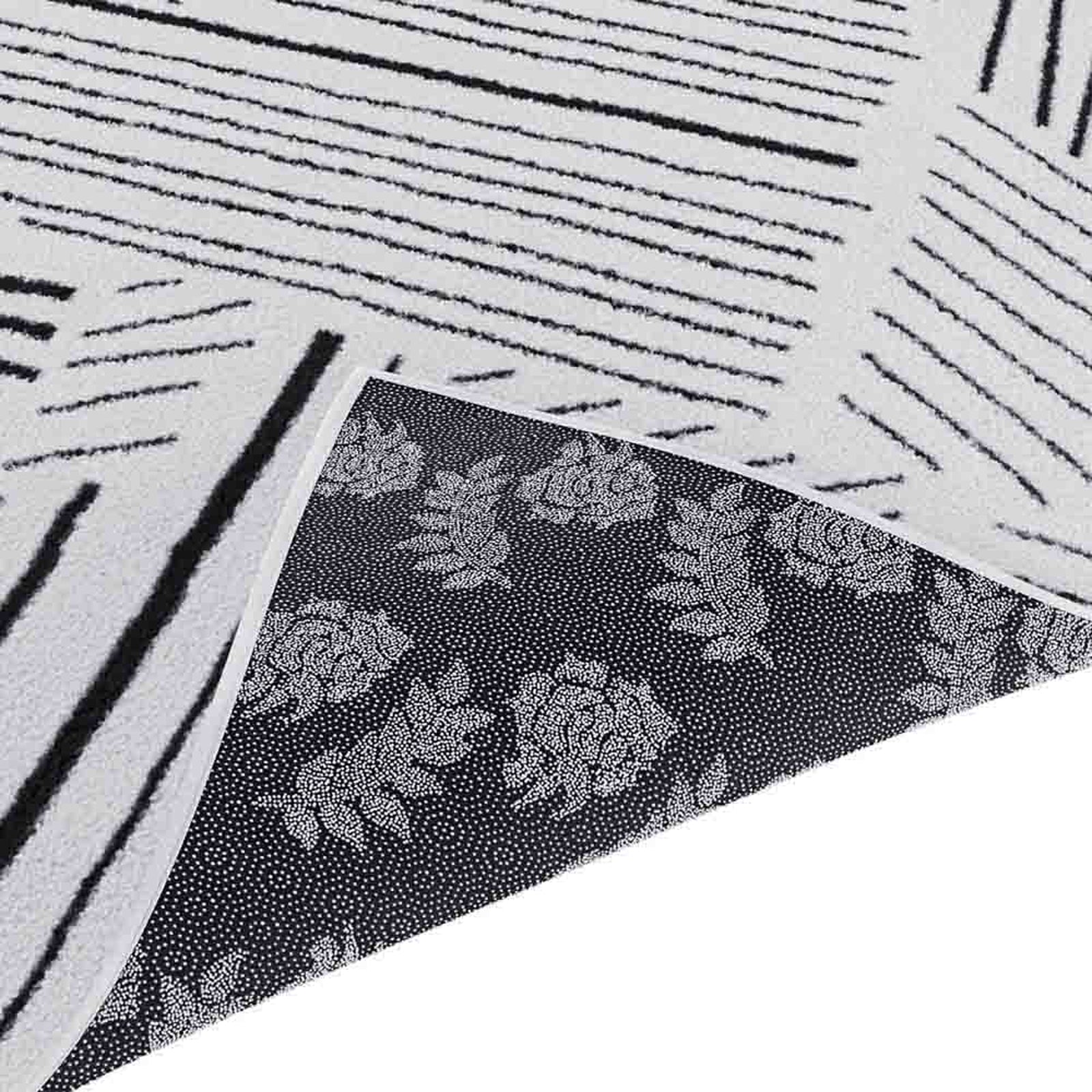 Vikki 120x170cm Small Abstract Contemporary Floor Rug flipped to show white linear-striped upper side and floral motif underside, highlighting its modern monochrome design and durable construction.