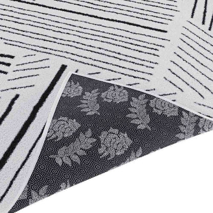 Vikki 120x170cm Small Abstract Contemporary Floor Rug flipped to show white linear-striped upper side and floral motif underside, highlighting its modern monochrome design and durable construction.