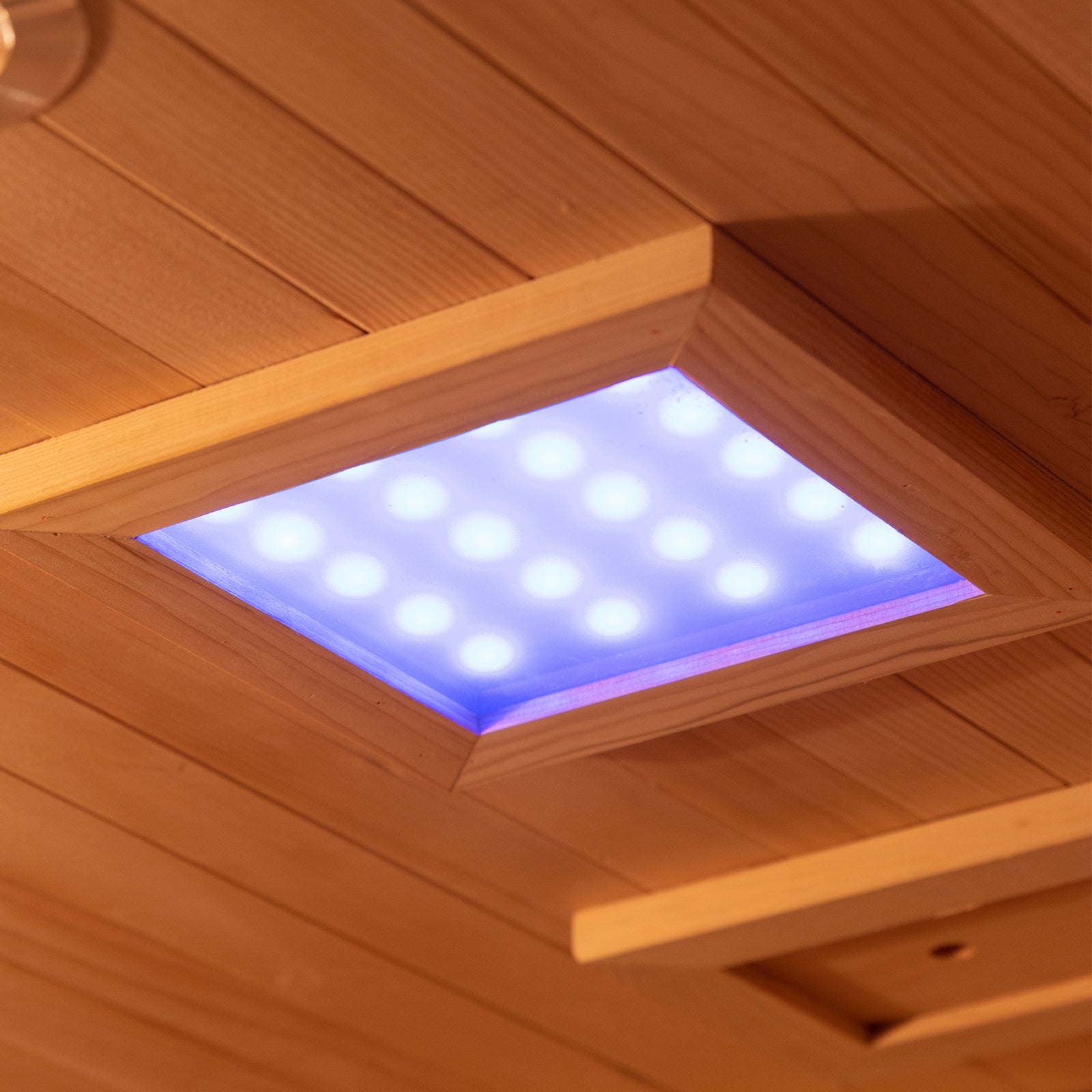 Harlow 1 Person Canadian Hemlock Infrared Home Sauna features a wood-paneled ceiling with a recessed square LED light in a wooden trim frame, enhancing the serene sauna atmosphere.
