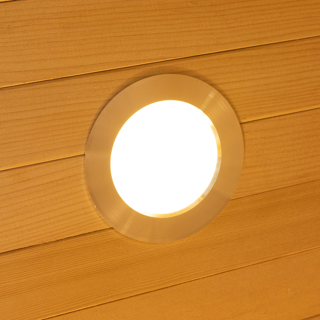 Harlow 1 Person Canadian Hemlock Infrared Home Sauna, featuring a round, recessed ceiling light in a wood-paneled ceiling, emitting a warm, diffuse glow for a cozy, indoor sauna experience.