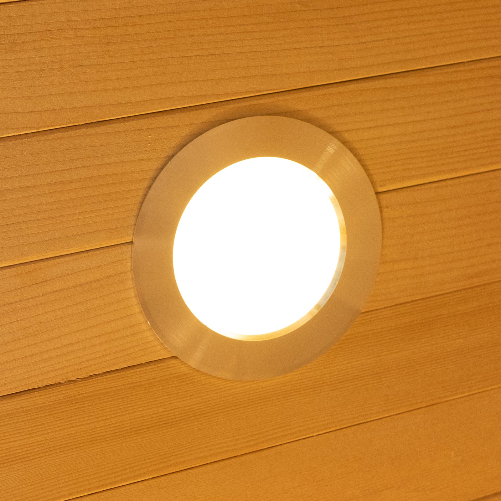 Harlow 1 Person Canadian Hemlock Infrared Home Sauna, featuring a round, recessed ceiling light in a wood-paneled ceiling, emitting a warm, diffuse glow for a cozy, indoor sauna experience.