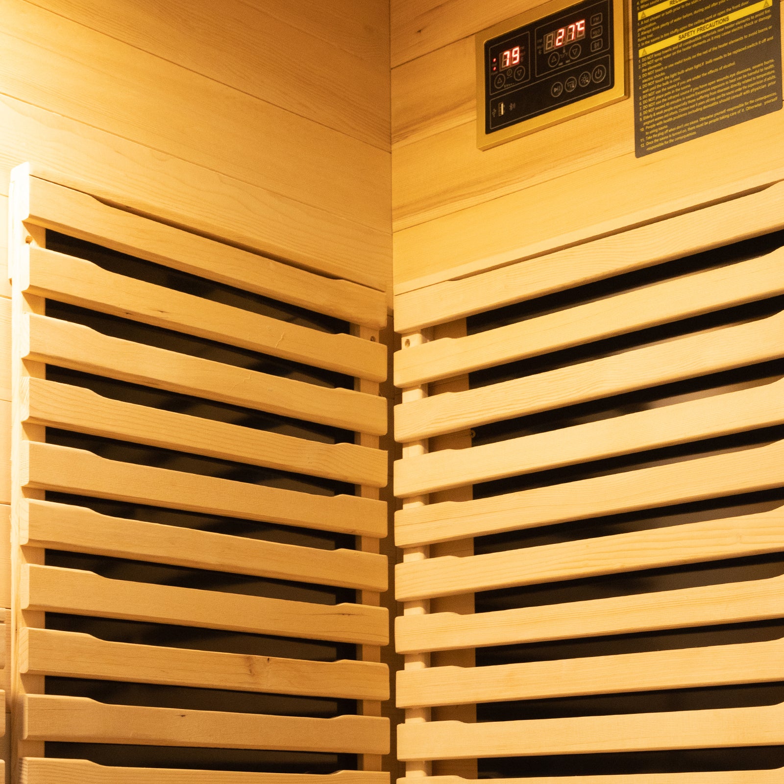 Interior of Harlow 2 Person Canadian Hemlock Infrared Home Sauna, showcasing light-colored wooden slats, digital control panel, and safety label, highlighting the sauna's modern design and functionality.