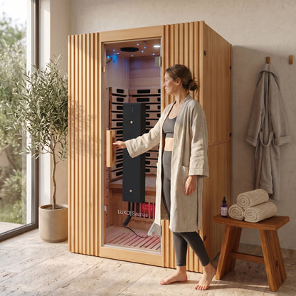 Wooden infrared sauna with vertical slat exterior, glass door open showing red heating panels and blue interior lighting