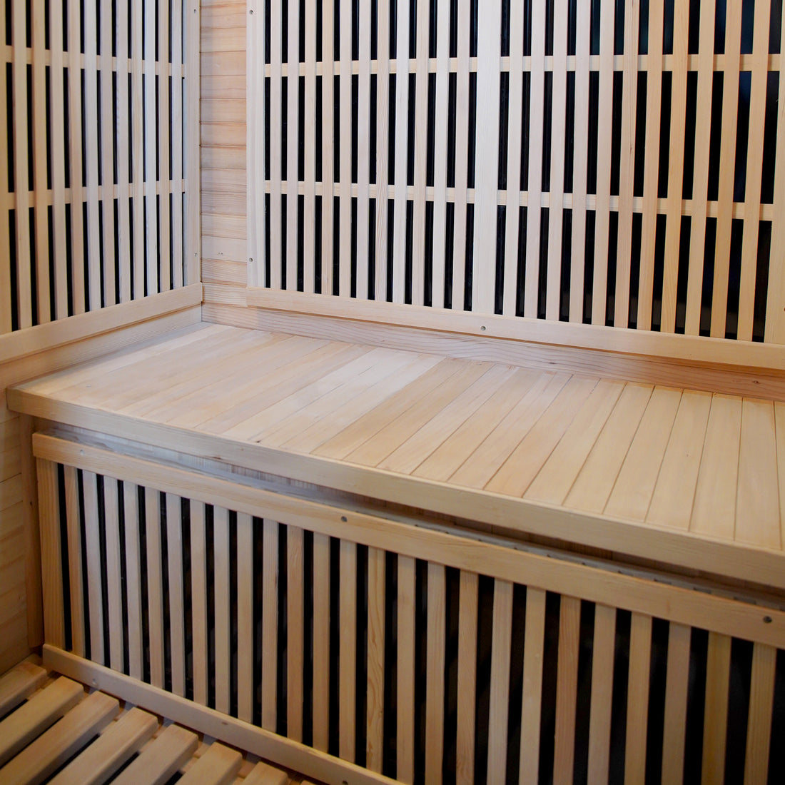 Hirsi 2 Person Carbon Fibre Infrared Indoor Home Sauna interior with light-toned wooden benches and slatted walls, showcasing a spacious design ideal for home relaxation and detoxification.