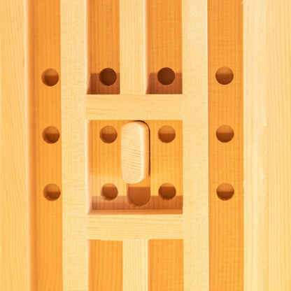 Close-up of the Hoito 4-Person Full Spectrum Infrared Sauna showcasing vertical wooden slats framing a recessed square with drilled holes and a thumb-shaped wooden latch, reflecting its ventilated design.