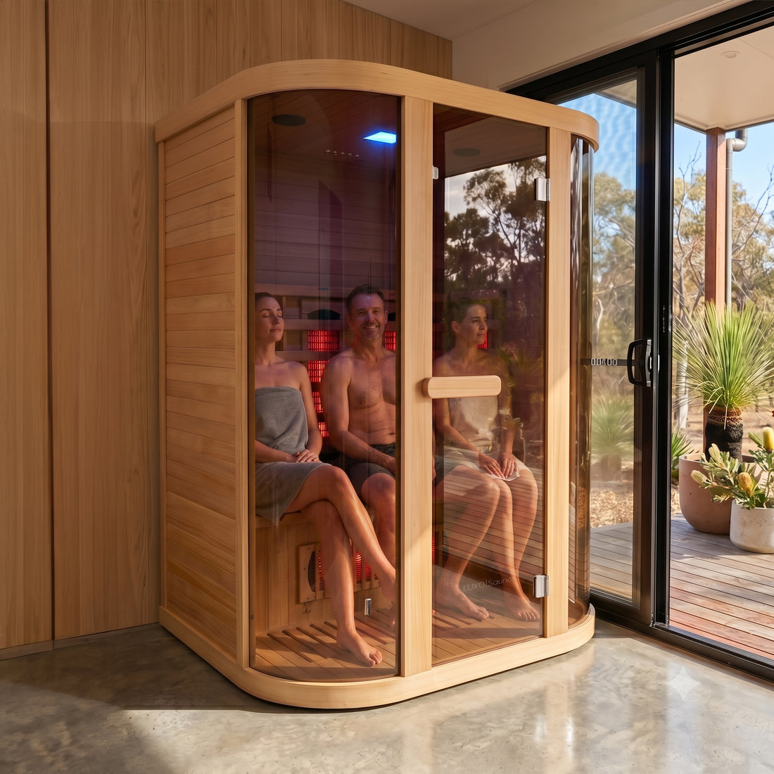 Corner infrared sauna with curved glass front and wooden interior, showing red heating elements and blue chromotherapy light