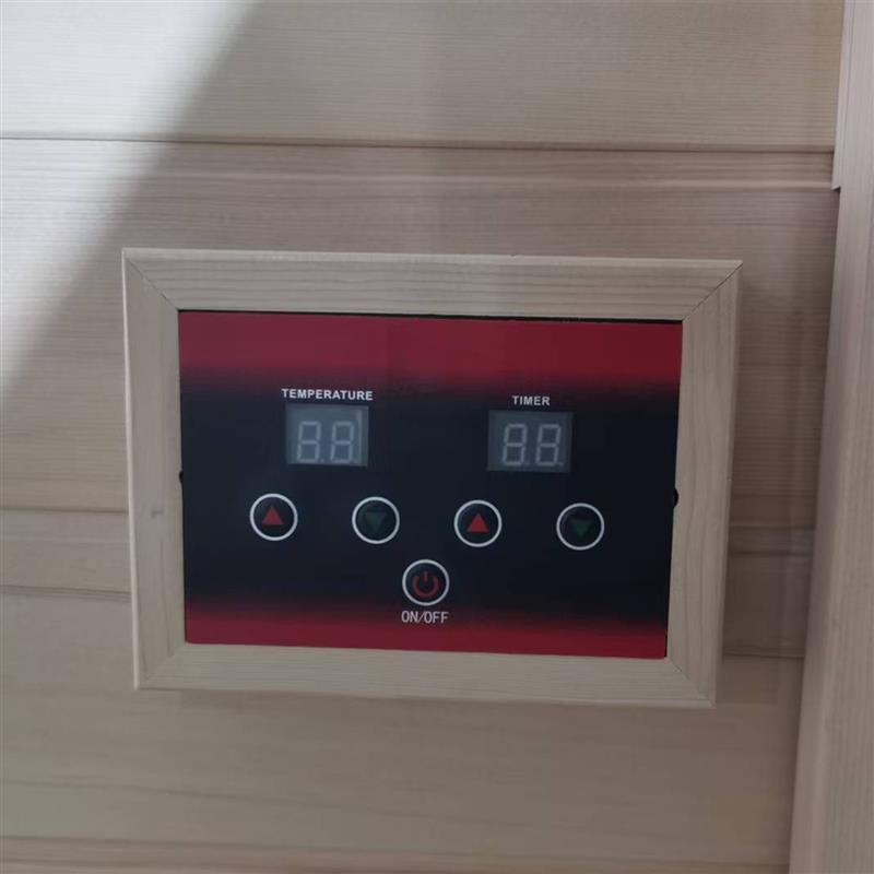 Jarli 1 Person Portable Compact Infrared Indoor Home Sauna features a digital control panel with labeled buttons for temperature and timer adjustments, framed in light wood, mounted on a wooden wall.