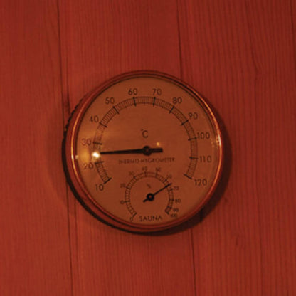 Round analog sauna gauge on a wooden wall for the Kivi 3-Person Traditional Stove Finnish Indoor Home Sauna, showing temperature just under 30°C and humidity, enhancing the sauna experience.