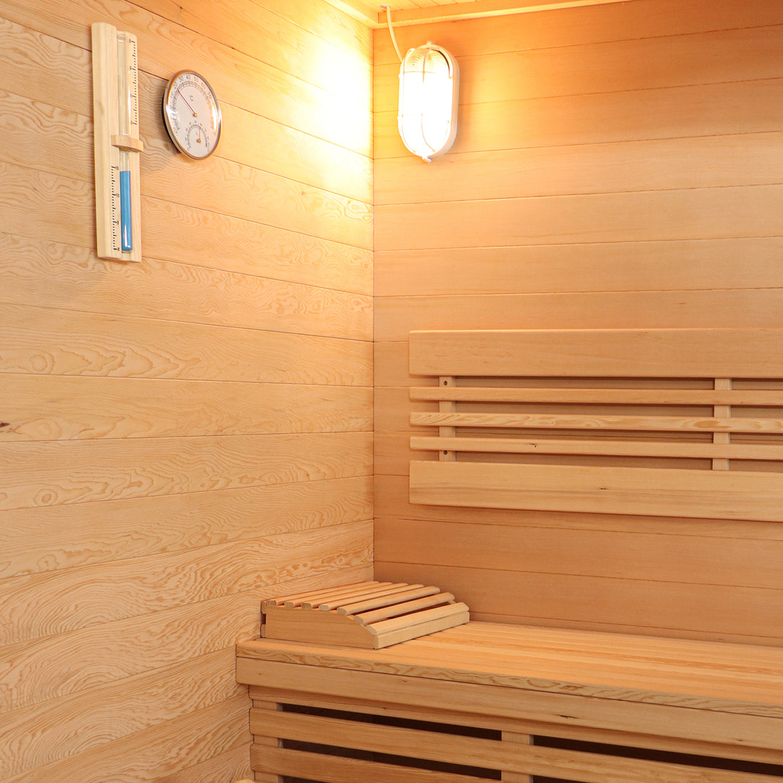 Kivi 4-Person Traditional Finnish Home Sauna interior with light wood paneling, bench seating, headrest, wall-mounted thermometer/hygrometer, and light fixture, showcasing spacious and relaxing sauna environment.