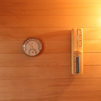 Close-up of the Kivi 4-Person Traditional Finnish Outdoor Sauna, highlighting wood panel detail, temperature gauge, and measuring device, emphasizing the craftsmanship and functionality of this outdoor sauna experience.