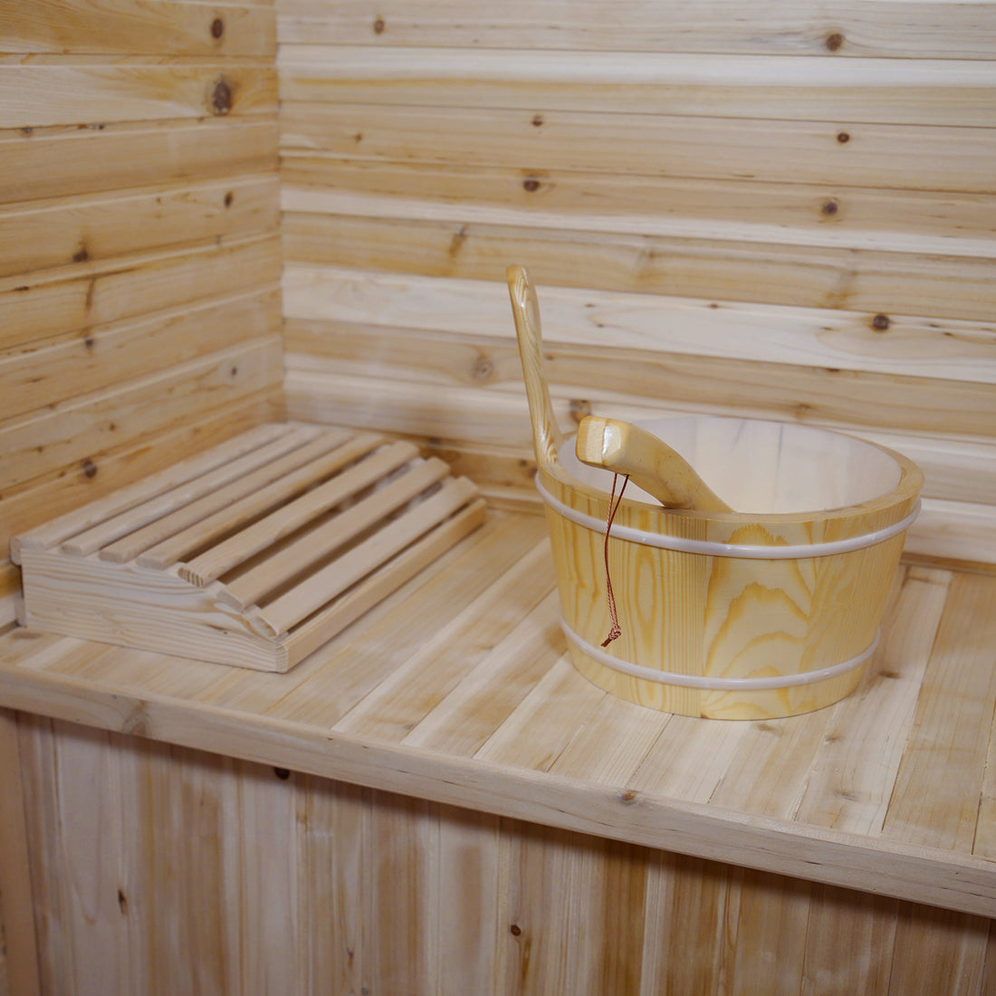 Kivi 4-Person Traditional Outdoor Finnish Home Sauna featuring light timber paneling, wooden bench with slatted headrest, and a wooden bucket with ladle, exemplifying elegant craftsmanship for a personal spa retreat.