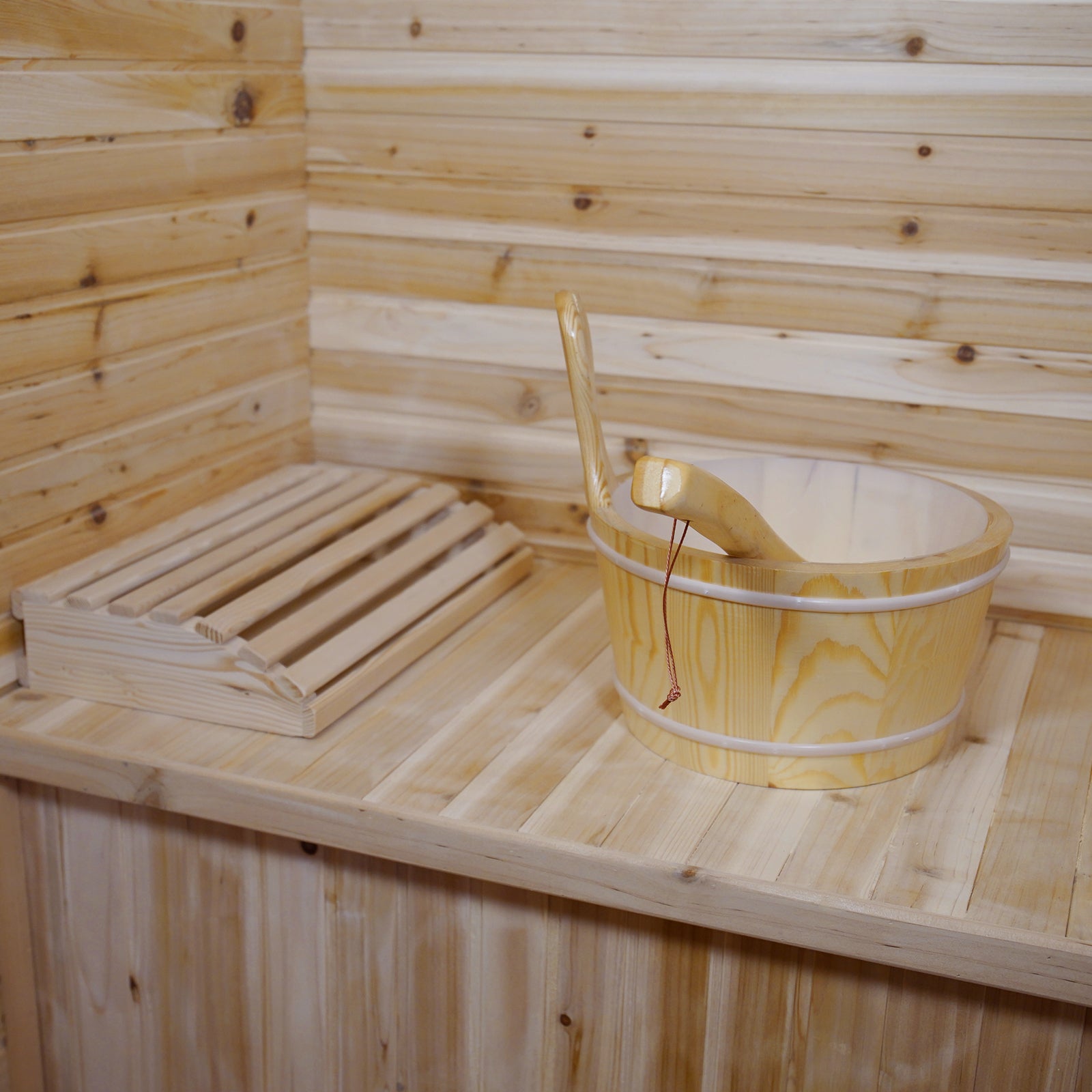 Kivi 4-Person Traditional Outdoor Finnish Home Sauna featuring light timber paneling, wooden bench with slatted headrest, and a wooden bucket with ladle, exemplifying elegant craftsmanship for a personal spa retreat.