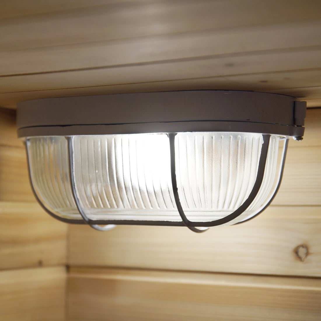 Kivi 4-Person Traditional Outdoor Finnish Home Sauna featuring a ribbed glass diffuser and metal cage ceiling light mounted on wooden paneling, casting an inviting glow for a serene sauna experience.