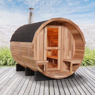 Luola 4-Person Red Cedar Barrel Sauna with Wood Stove, featuring a traditional barrel shape, chimney, and wooden bucket, set outdoors, showcasing its luxurious, natural design and spaciousness for relaxation.
