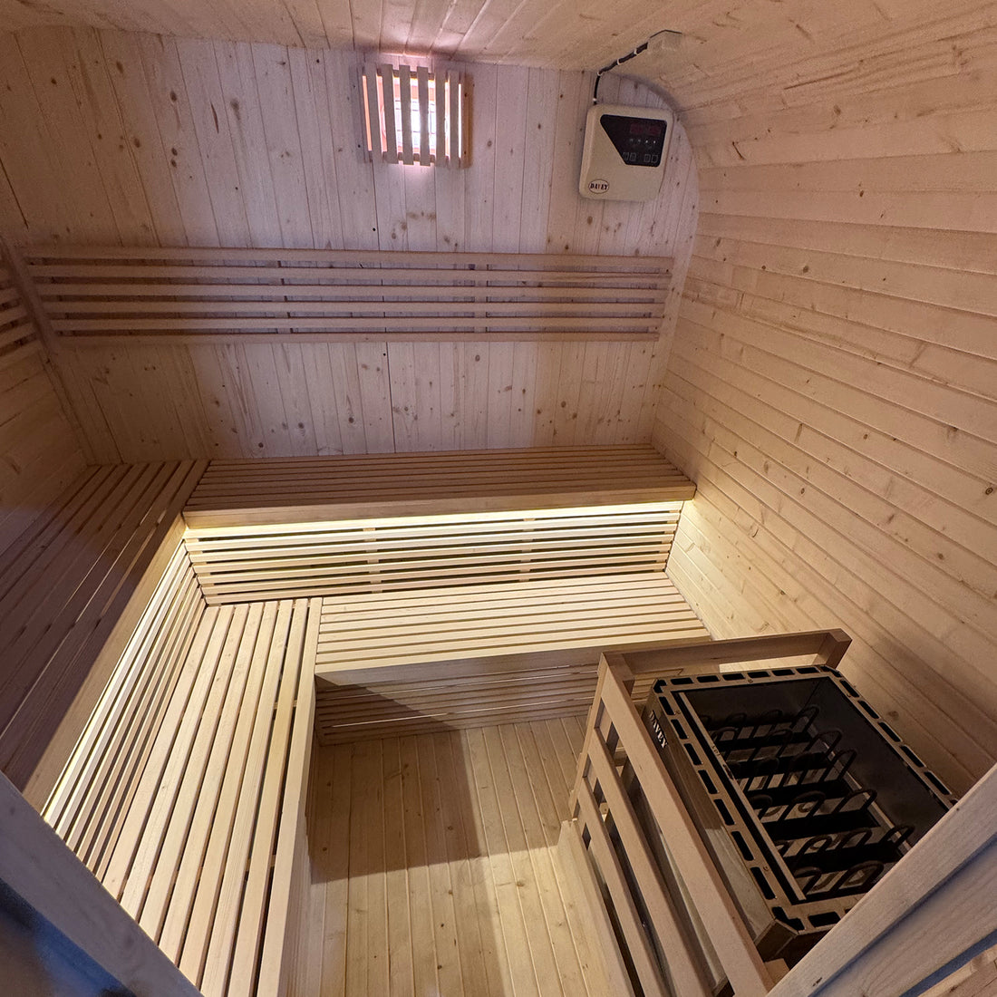 Medika 8 Person Traditional Finnish Outdoor Sauna close-up, showcasing its sleek wooden interior with two-level benches, emphasizing spaciousness and modern design, set inside a wooden sauna environment.